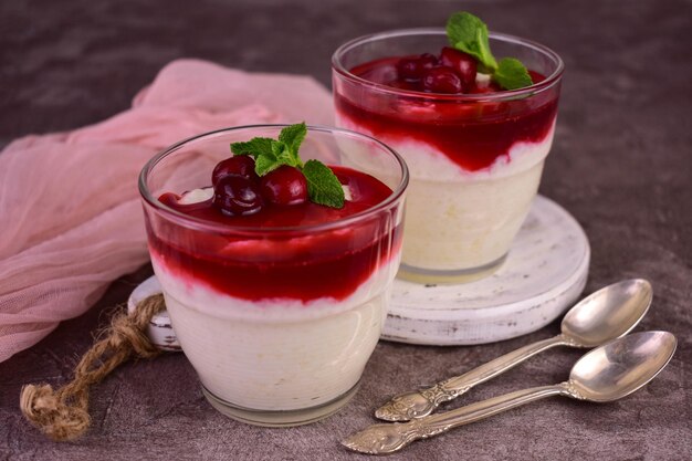 Deux verres de pudding maison aux cerises sur une table en bois