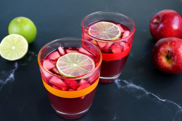 Deux verres de sangria de vin rouge sur la table avec des limes floues et des pommes en arrière-plan