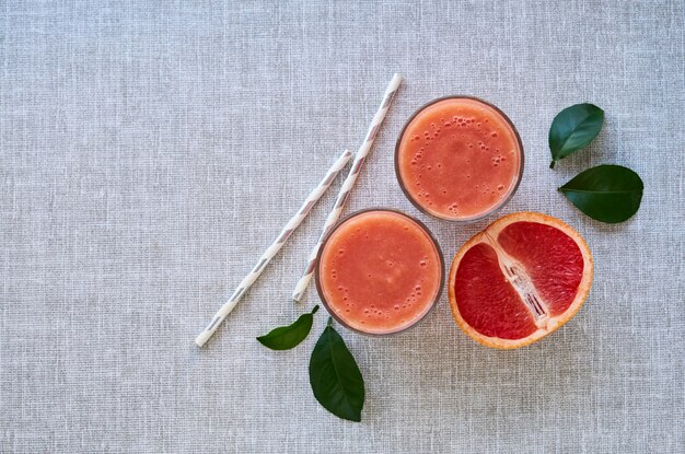 Deux verres de smoothie au pamplemousse sur fond gris