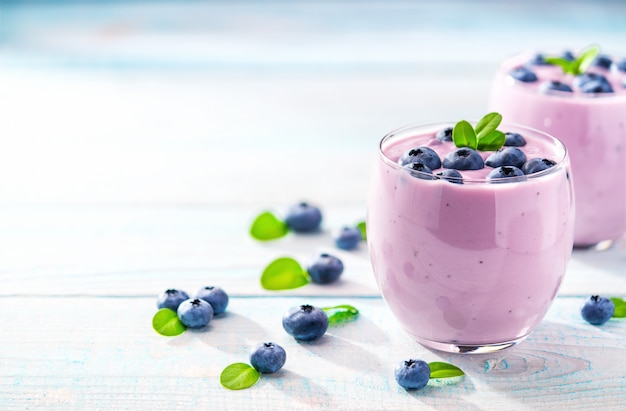 Deux verres de smoothie aux bleuets sur un fond en bois turquoise