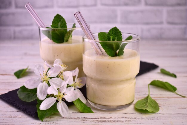 Deux verres de smoothie pomme et banane sur un fond en bois blanc