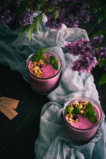 Deux verres avec des smoothies aux mûres sur la table au soleil