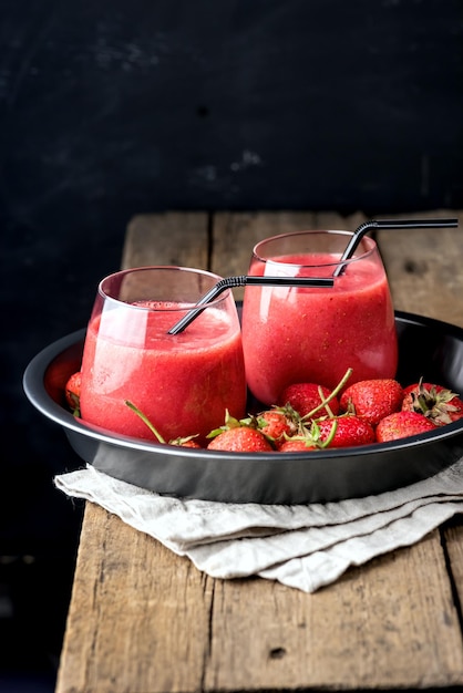 Deux verres de smoothies rafraîchissants à la fraise et à la pêche au citron sur fond noir