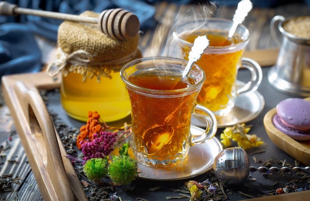 Photo deux verres de thé avec un pot de miel et un pot de miel sur la table.