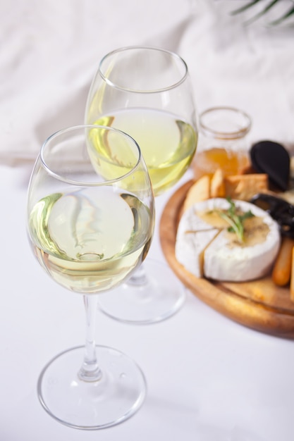 Deux verres de vin blanc et assiette avec assortiment de fromages, fruits et autres collations pour la fête