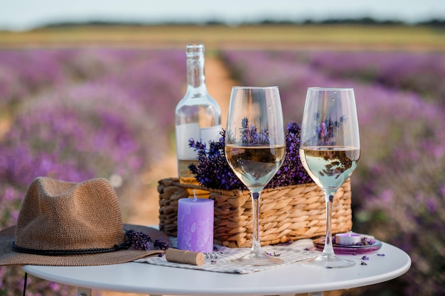 Deux verres de vin blanc et une bouteille dans un champ de lavande à Provance Fleurs violettes en arrière-plan