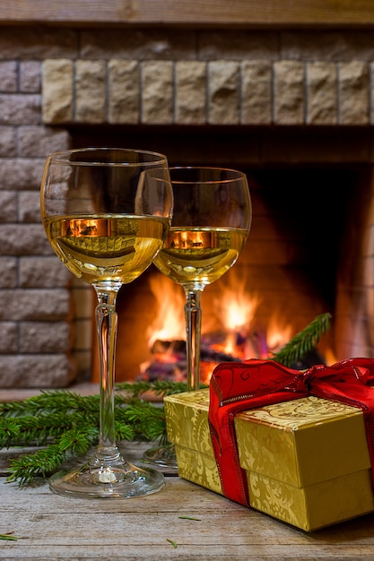 Deux verres de vin blanc, cadeau de Noël dans une boîte près de l&#39;espace de feu confortable.