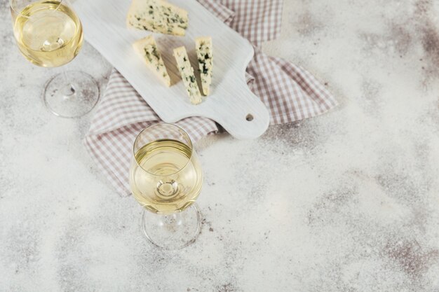 Deux Verres De Vin Blanc Servi Avec Plateau De Fromages Sur Une Surface Blanche. Concept D'humeur De Vin.