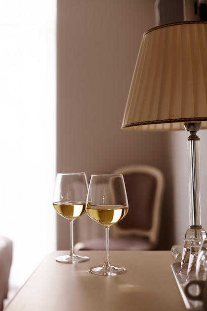 Deux verres de vin blanc sur la table à côté de la lampe