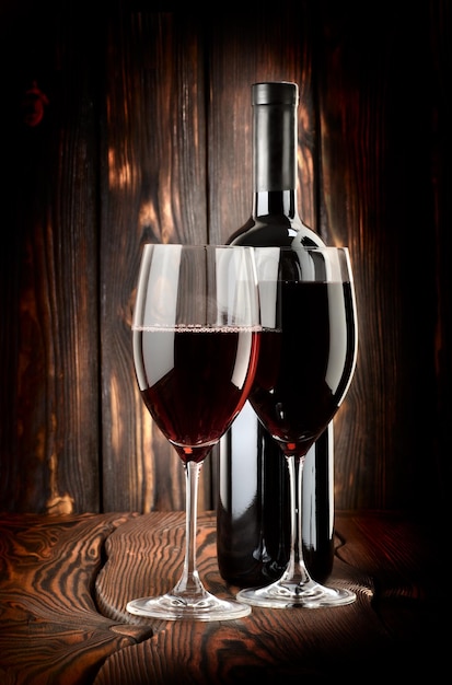 Deux verres de vin et une bouteille de vin sur un fond en bois