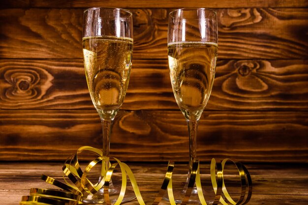 Deux verres à vin avec champagne et ruban doré sur une table en bois rustique