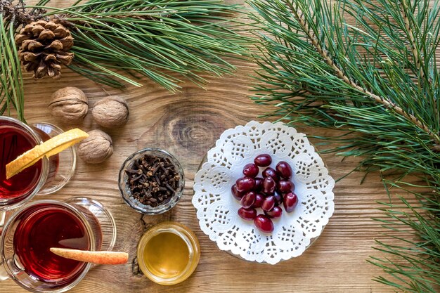 Deux verres de vin chaud avec des bâtons de cannelle tranche d'oranges et d'anis étoilé pomme sur une table en bois