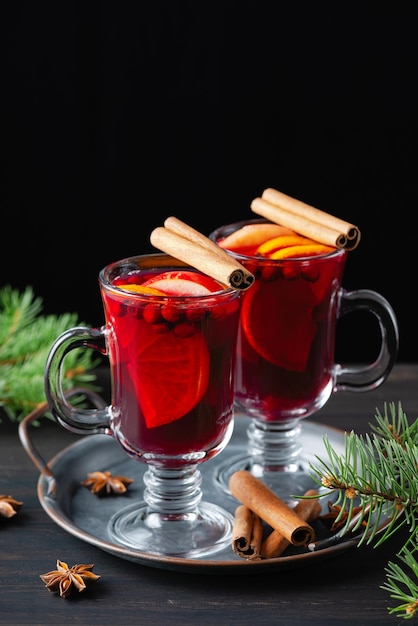 Deux verres de vin chaud à l'orange et aux épices sur fond de bois