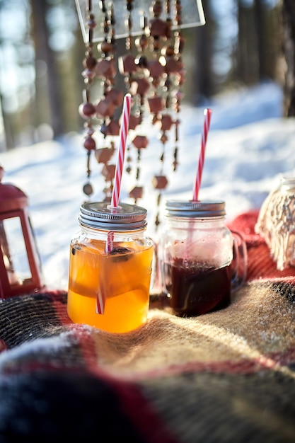 Deux verres de vin chaud se tiennent sur une couverture dans une forêt de pins d'hiver