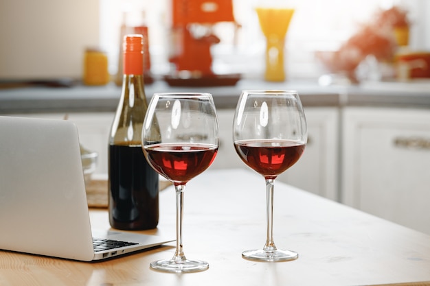 Deux verres à vin avec du vin rouge sur un comptoir de cuisine en bois