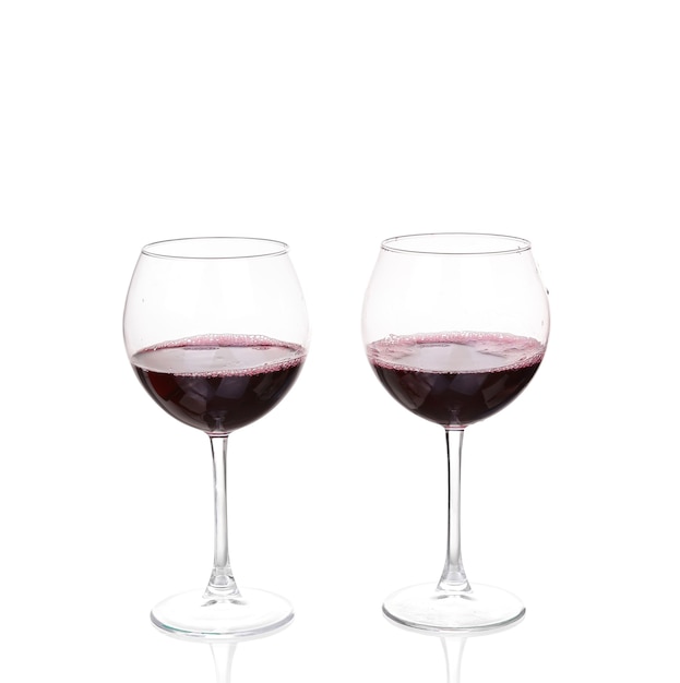 Deux verres à vin avec du vin rouge sur mur blanc