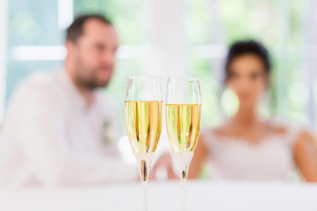 Deux verres de vin sur le fond flou de la mariée et du marié.