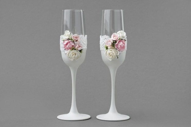 Deux verres à vin de mariage décorés de dentelle et de roses sur fond gris