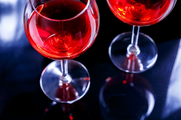 Deux Verres De Vin Rouge Au Bar, Discothèque Sur Fond Noir Avec Reflet.