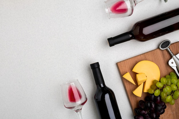 Deux verres de vin rouge, fromage et raisins vue de dessus