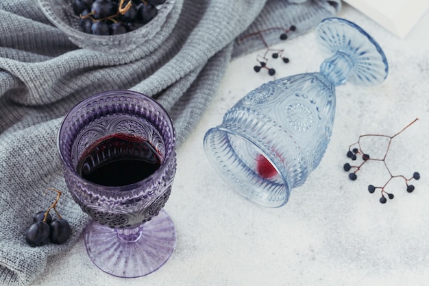 Deux verres de vin rouge avec un livre, des raisins noirs et des baies sèches sur une lumière