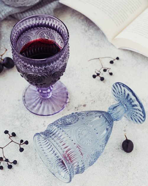 Deux verres de vin rouge avec un livre, des raisins noirs et des baies sèches sur une lumière