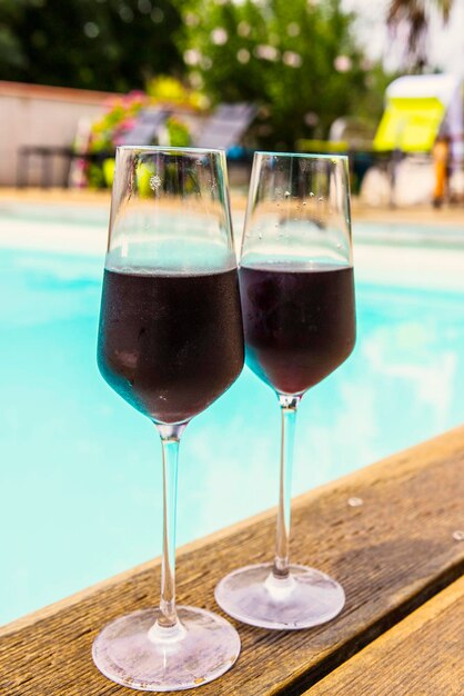 Deux verres de vin rouge près de la piscine, espace détente près de la piscine, vacances d'été.