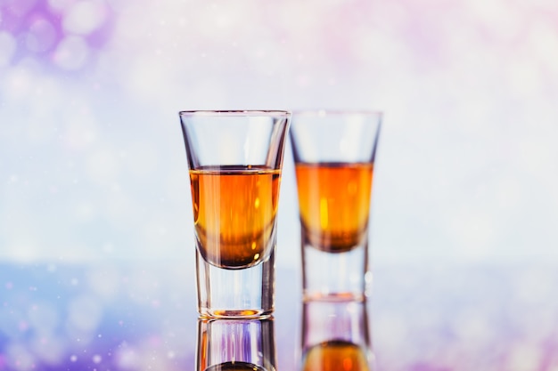 Deux verres de whisky ou de bourbon avec décoration de Noël sur un léger bokeh