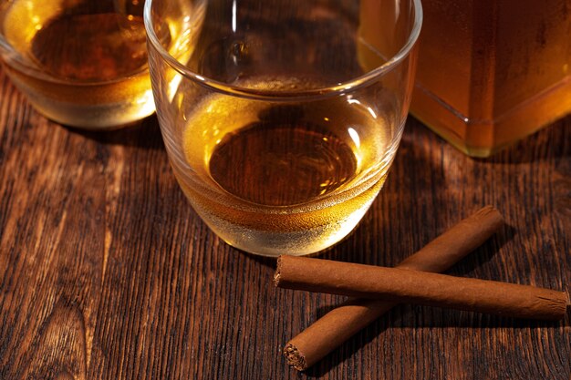 Deux verres de whisky et cigares sur table en bois