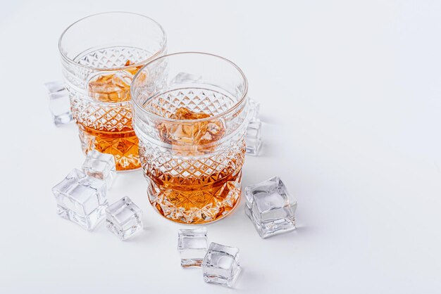 Deux verres de whisky avec de la glace sur un fond blanc avec place pour le texte