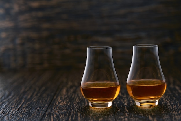 Deux verres de whisky servis sur table en bois avec espace copie.