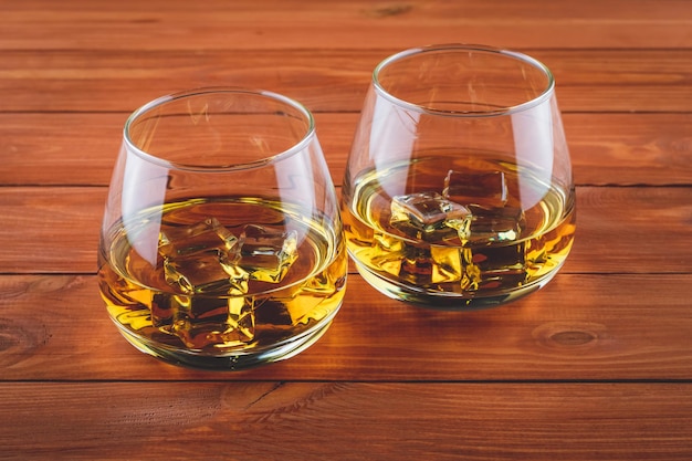 Deux verres de whisky sur une table en bois marron. Un verre de bourbon avec de la glace. Boisson forte. Eau-de-vie ancienne, cognac.