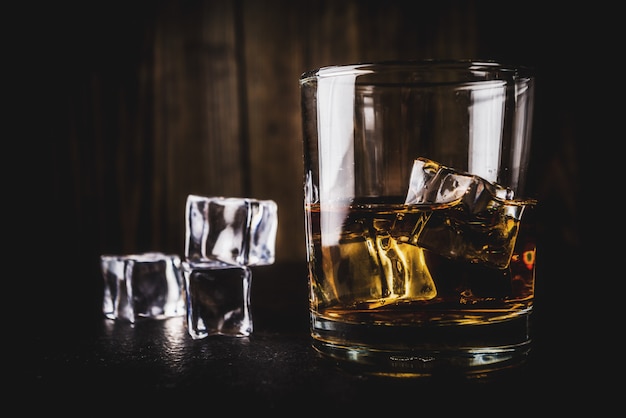 Deux verres à whisky sur une table en bois sombre avec des glaçons