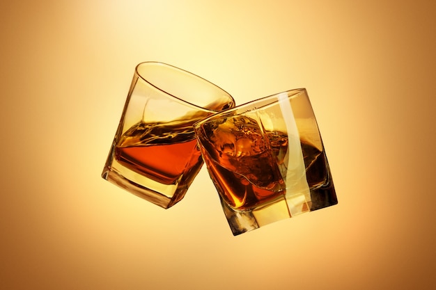 Deux verres à whisky tintant ensemble sur fond de studio marron