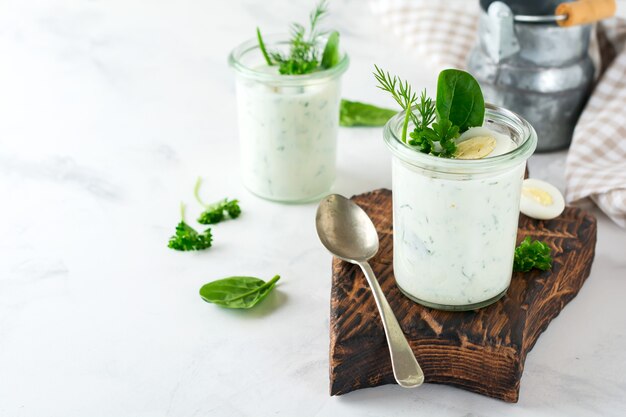 Deux verres de yogourt santé avec une variété d'herbes, d'épinards, d'aneth, d'oignons, de persil et d'œufs de caille. Le concept d'un petit-déjeuner végétarien sain. Mise au point sélective.