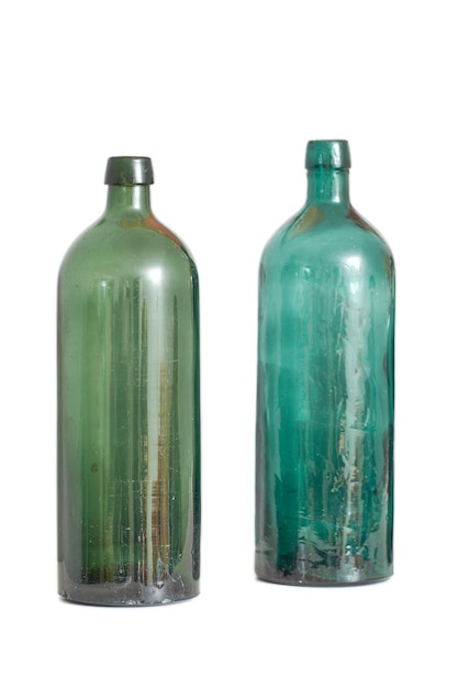 Deux vieilles bouteilles en verre vides isolées sur un fond de studio blanc avec espace pour copie Verrerie antique colorée utilisée comme pièce d'art décoratif Conteneurs vintage transparents à recycler ou à réutiliser