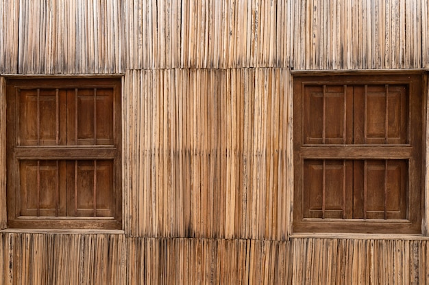 Deux vieilles fenêtres fermées en bois dans un mur de paille avec espace pour copie