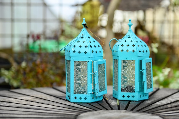 Photo deux vieilles lanternes vintage turquoises debout sur une table de jardin rustique ronde à l'extérieur