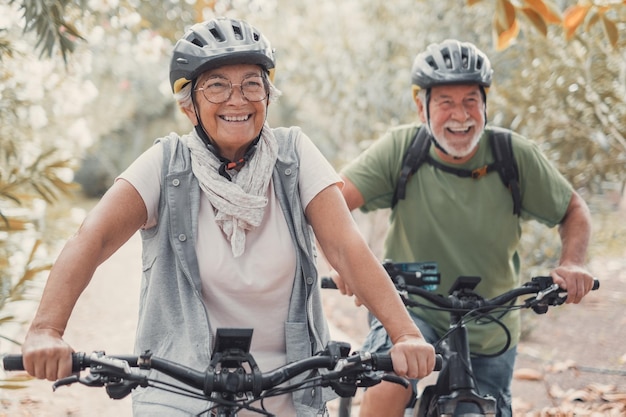 Deux vieilles personnes âgées et heureuses qui s'amusent et font du vélo ensemble pour être en forme et en bonne santé à l'extérieur