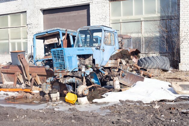 Deux vieux tracteurs bleus cassés se tiennent dehors au printemps.