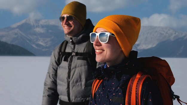 Photo les deux voyageurs avec des sacs à dos debout sur un fond de montagnes enneigées