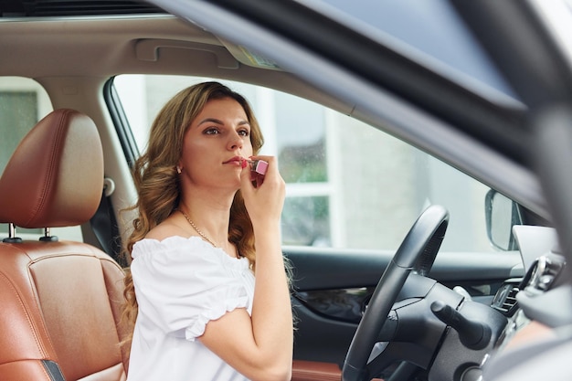 Devant le volant Une jeune femme en vêtements décontractés est assise dans sa voiture pendant la journée