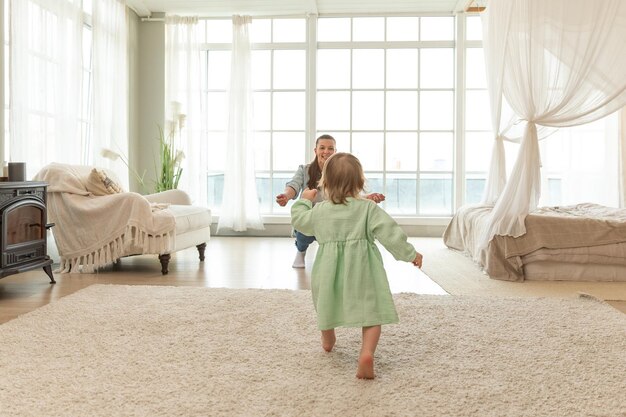 Développement de bébé mignon petit bébé fille faisant ses premiers pas à la maison heureux moter souriant regardant un