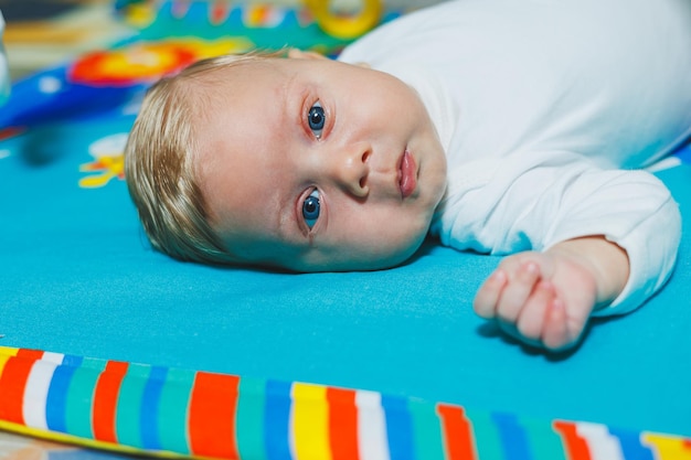 Développement de l'enfant Le bébé est allongé sur le tapis de développement et joue avec des jouets Pendant le jeu, l'enfant apprend à connaître le monde et apprend les formes et les couleurs