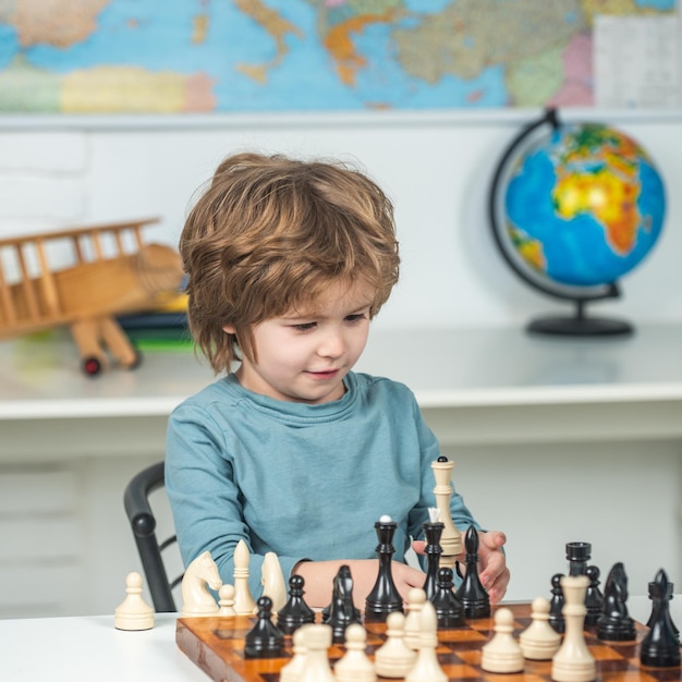Développement précoce des enfants Joli petit garçon concentré assis à la table et jouant aux échecs