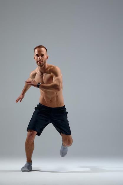 Développer l'endurance Athlète masculin en mouvement isolé sur fond de studio gris Maintenir la santé et la force Concept de mouvement de mode de vie sain sport