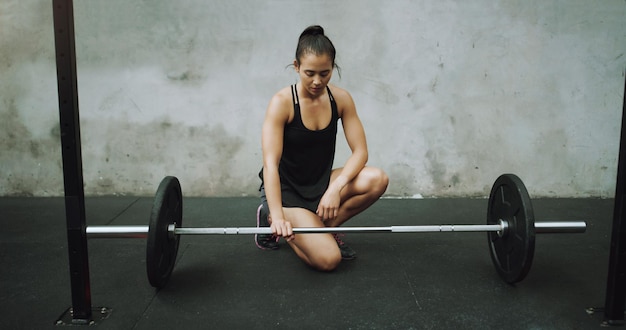 Développer l'état d'esprit nécessaire pour déplacer des montagnes Photo d'une jeune femme faisant de l'exercice avec une barre dans une salle de sport