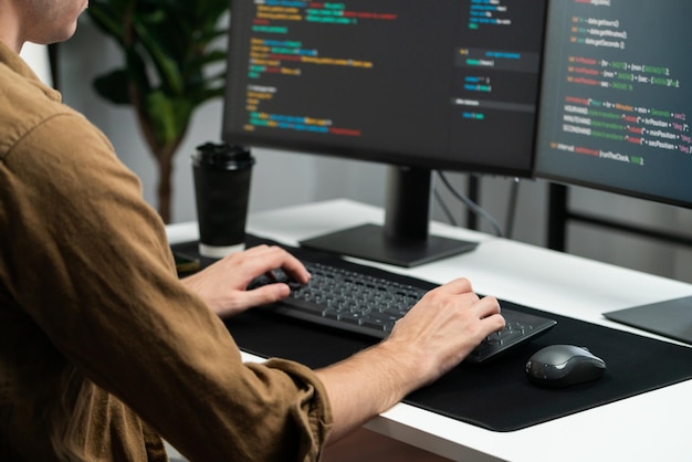 Développeur informatique travaillant sur le développement de logiciels en ligne sur des moniteurs PC dans un bureau à domicile moderne sur des écrans d'application de codage créant la dernière mise à jour du programme, du firmware, de l'information, du concept de la version Gusher
