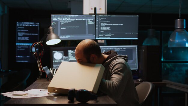 Un développeur de logiciels mangeant de la pizza livrée à emporter