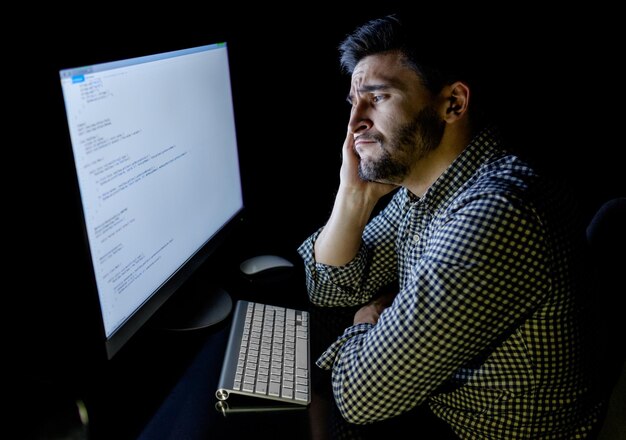 Développeur de logiciels ordinateur dans le bureau à domicile sombre Démarrage et concept de travail dur
